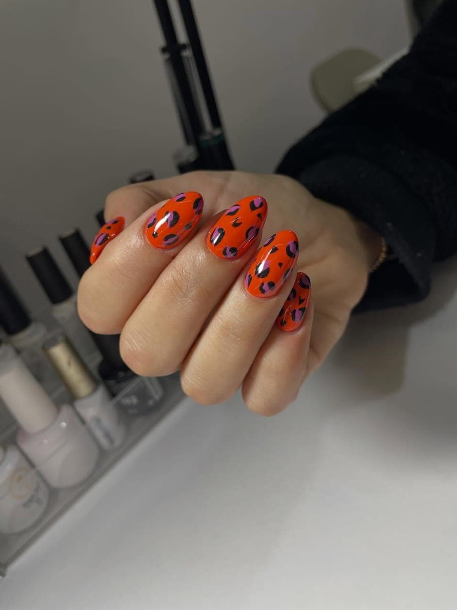 Bright orange almond nails with pink and black leopard print