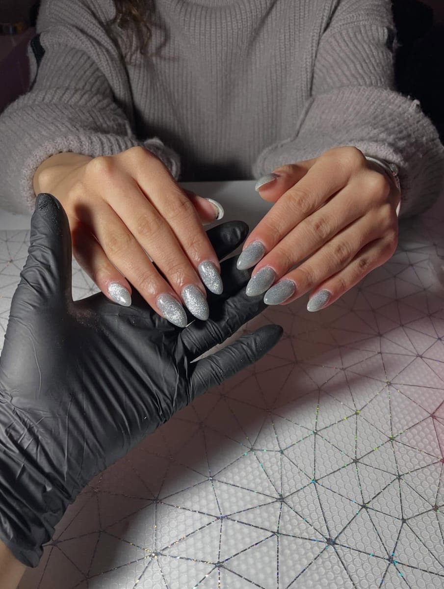 Silver glitter almond nails shown by the nail artist